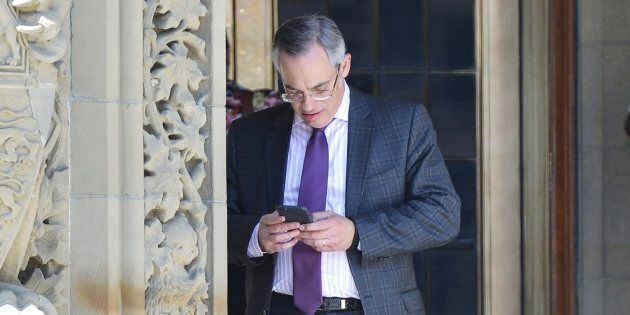 Conservative MP Tony Clement checks his phone on Parliament Hill in Ottawa on May 11, 2016.