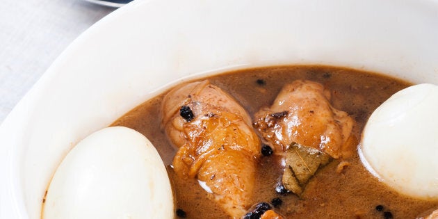 A serving of adobo with eggs. Recipe comprises chicken braised in soy sauce, vinegar pepper and bay leaves.