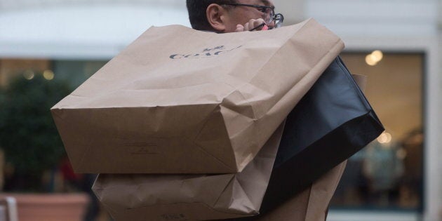 A man carries shopping bags of Boxing Day sale purchases at the McArthur Glen Designer Outlet mall, in Richmond, B.C., on Dec. 26, 2017.