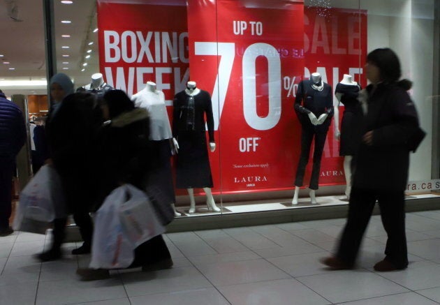 People walk past a clothing store during Boxing Day sales at a mall in Ottawa on Dec. 26, 2017.