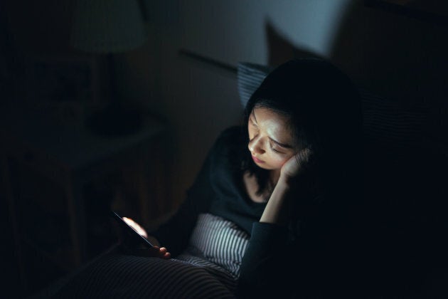 Tired woman fell asleep while using smartphone in bed at night