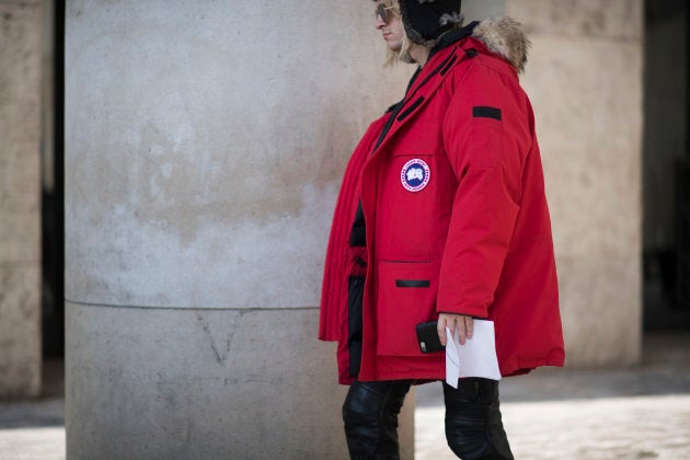 A guest is seen wearing a a red Canada Goose jacket in the streets of Paris during Paris Fashion Week.