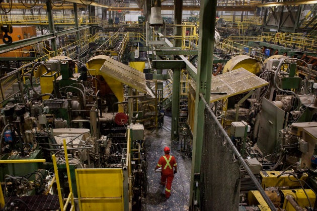 An employee walks between machines that process logs at the West Fraser Timber Co. sawmill in Quesnel, B.C. on June 5, 2015.