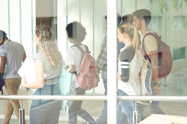 Students walking in school corridor, viewed through window