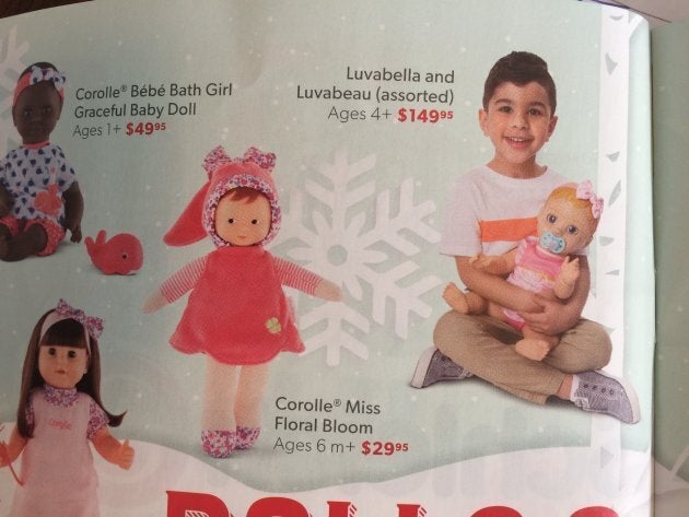 A little boy holds a baby doll in Indigo's "What Kinds Want" holiday catalogue.