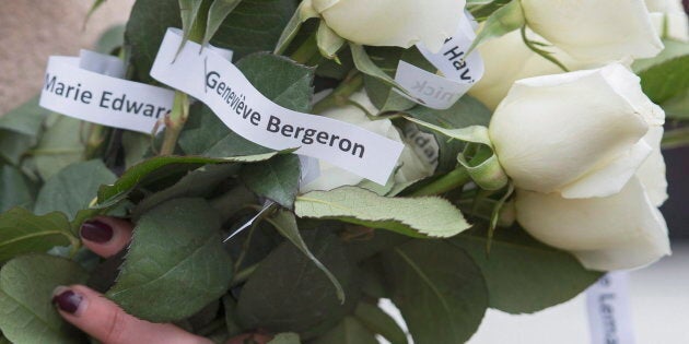 A woman holds white roses adorned with the names of fourteen murdered female students during a ceremony in Montreal, Dec. 6, 2015, to remember the victims of the Polytechnique massacre on Dec. 6, 1989.