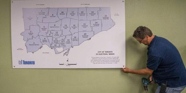 A City employee puts up the map with the 25 council seats on the wall inside the city hall elections office in September.