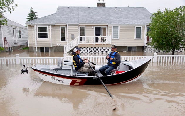 Two men use a fishing boat to rescue residents from a neighborhood after heavy rains caused flooding, closed roads, and forced evacuation in High River, Alta., in June of 2013.