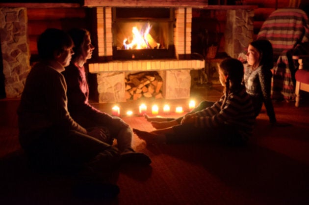 A family relaxing by a fire and candlelight.