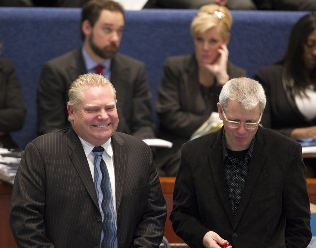 Doug Ford laughs while speaking with Adam Vaughan during a Toronto City Council meeting on Jan. 29, 2014.