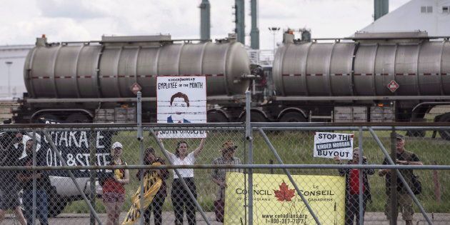 Protestors stand outside the fence as Prime Minister Justin Trudeau visits a Kinder Morgan facility in Edmonton on June 5, 2018.