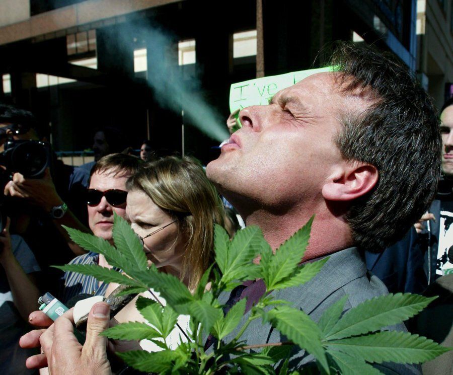 Marc Emery smokes marijuana as he holds a plant at a gathering of pro-marijuana legalization supporters outside police headquarters in Toronto on June 19, 2003.
