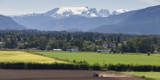 A farmer on a tractor prepares the land in Comox Valley, B.C. under the Comox Glacier.