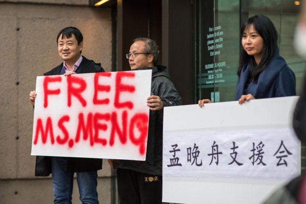 People hold signs in support of Meng Wanzhou outside of a bail hearing at the Supreme Court in Vancouver on Dec. 11, 2018.