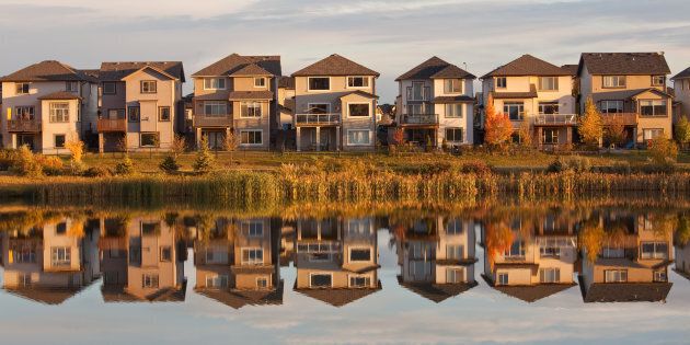 A row of houses reflected in a pond in Calgary, Alta.