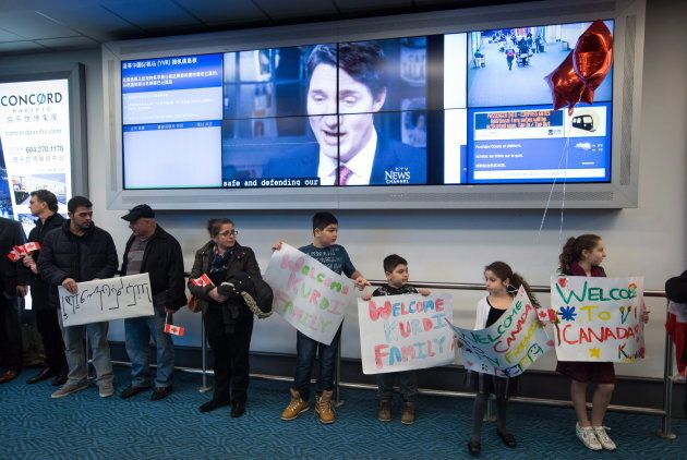 A television interview with Prime Minister Justin Trudeau plays on a screen as family and friends wait to welcome Syrian refugees Mohammad Kurdi and his family at Vancouver International Airport on Dec. 28, 2015.