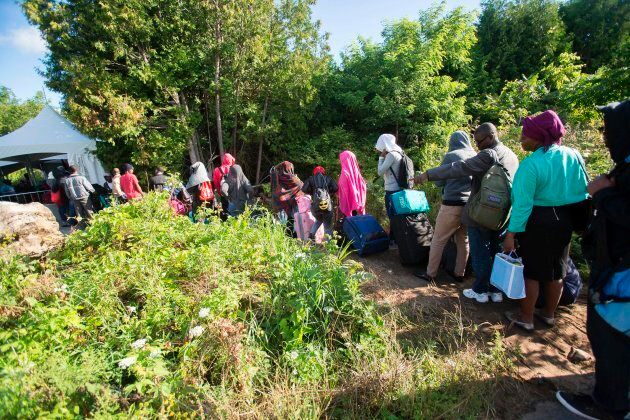 A long line of asylum seekers wait to illegally cross the Canada/U.S. border near Champlain, N.Y. on Aug. 6, 2017.