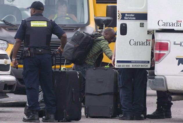 A man removes his belongings from a CBSA truck at a processing centre for asylum seekers at the Canada-United States border in Lacolle, Que. Aug. 10, 2017.