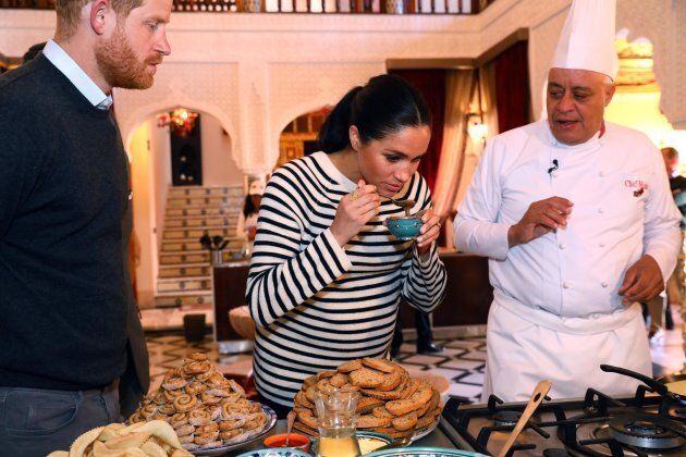 Meghan tries food as Prince Harry and Chef Moha Fedal look on during a cooking demonstration, where children from under-privileged backgrounds learn traditional Moroccan recipes from one of Morocco's foremost chefs.