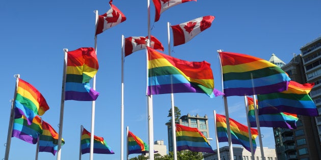 Rainbow colored gay pride flags and Canadian flags flutter in the wind beside English Bay in Vancouver’s West End Neighbourhood.