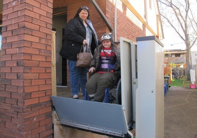 Jodi Dean helps her daughter Madison, who has epilepsy and severe osteoporosis, on an elevator as they leave home for a doctor's visit in Hamilton, Ont. on Nov. 21, 2017. The mother of three said basic income gave her family "the breathing room to not have to stress to put food on the table."