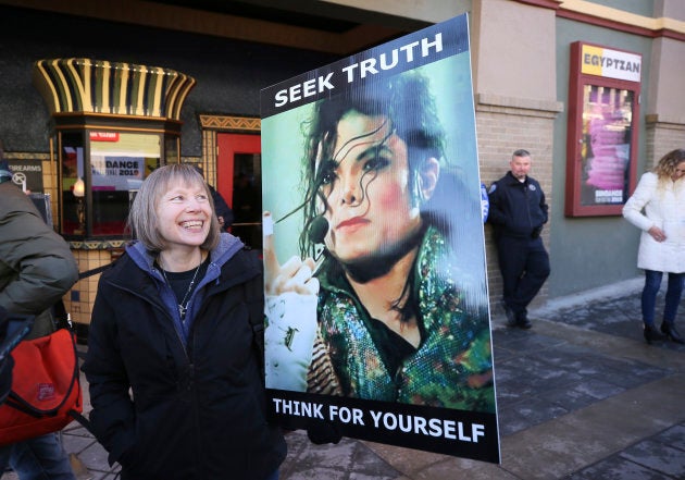 Brenda Jenkyns, who drove from Calgary, stands with a sign outside of the premiere of the "Leaving Neverland," during the 2019 Sundance Film Festival, Friday, Jan. 25, 2019, in Park City, Utah.