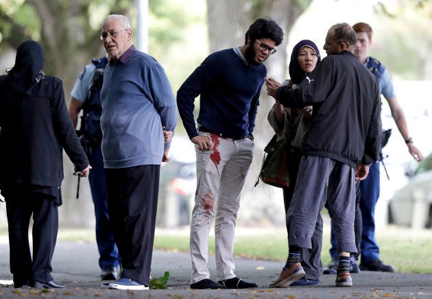 People stand across the road from a mosque in central Christchurch, New Zealand on Friday.