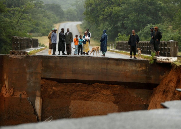 Locals look at a washed away bridge along Umvumvu river following Cyclone Idai in Chimanimani, Zimbabwe on March 18, 2019.