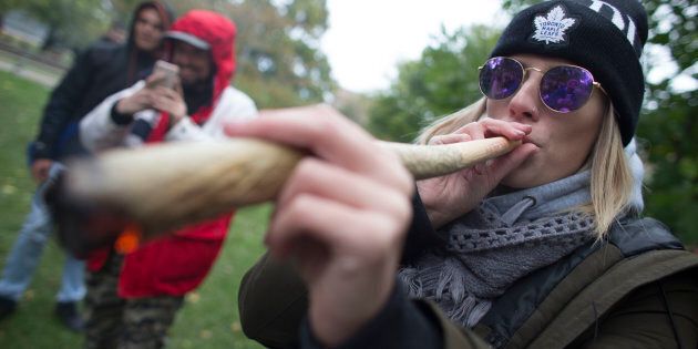 A woman smokes a somewhat oversized marijuana cigarette during a legalization party at Trinity Bellwoods Park, Toronto, Ont., Oct. 17, 2018.
