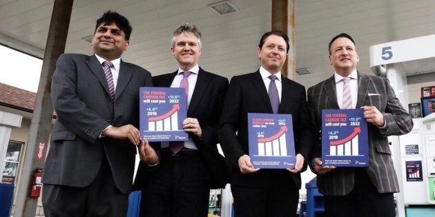 Ontario Progressive Conservative MPPs show off anti-carbon tax stickers. Their government will force gas stations to display the stickers or face fines of up to $10,000 a day.