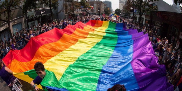 A giant rainbow flag is carried on Robson Street during the Vancouver Pride Parade on August 6, 2017. The Royal Canadian Mint says it plans to celebrate a 1969 government act that