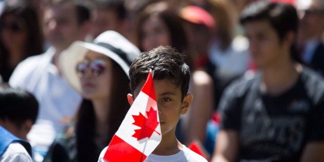 A young boy holds a Canadian flag while watching a special Canada Day citizenship ceremony in West Vancouver, B.C., on July 1, 2017.