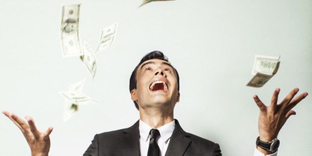 Businessman rejoicing for his success with hundred dollar bills. Money rain concept.