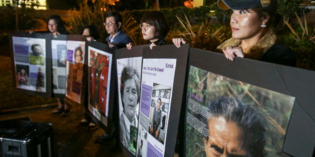 Supporters hold portraits of former 'Comfort Women' during a candlelight vigil in remembrance and support of 'Comfort Women', Japanese military sexual slavery victims during World War II, at Glendale Peace Monument on January 5, 2016 in Glendale, California. AFP PHOTO / Ringo Chiu / AFP / RINGO CHIU (Photo credit should read RINGO CHIU/AFP/Getty Images)