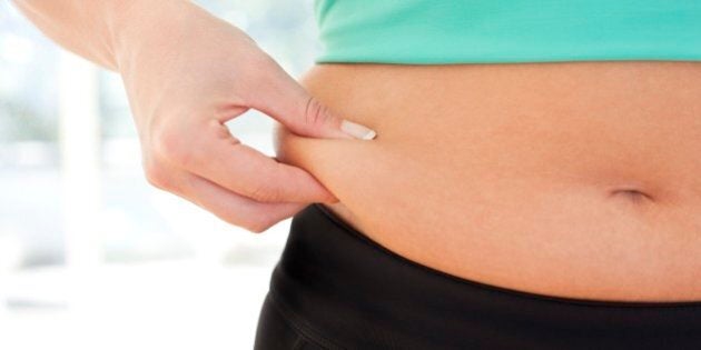 Weight loss. Woman pinching fat around her waist.