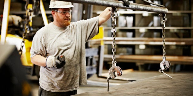 Steel worker preparing to move sheet of steel with crane