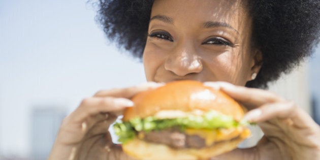 African American woman eating cheeseburger