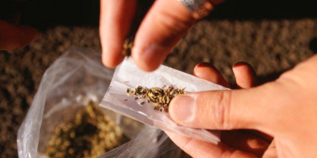 Person rolling joint, close-up of hands and bag of marijuana