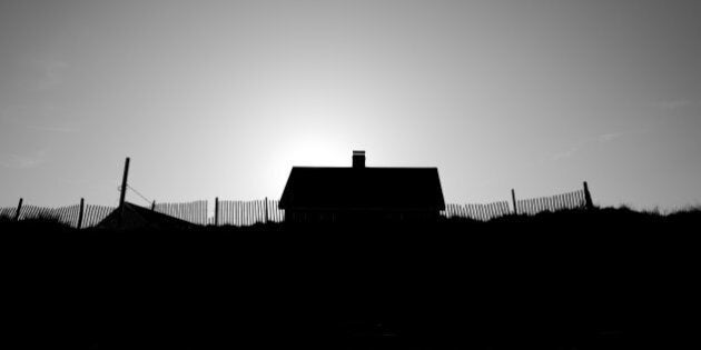 A small house on the beach surrounded by fencing.