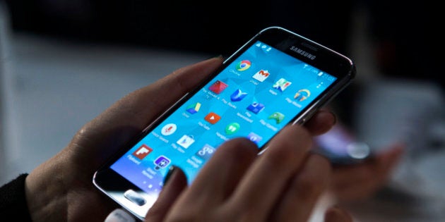 Attendees inspect Galaxy S5 smartphones on display during a Samsung Electronics Co. news conference on the opening day of the Mobile World Congress in Barcelona, Spain, on Monday, Feb. 24, 2014. Top telecommunication managers will rub shoulders in Barcelona this week at the Mobile World Congress, Monday, Feb. 24 - 27, a traditional venue for showcasing the latest products for dealmaking. Photographer: Angel Navarette/Bloomberg via Getty Images