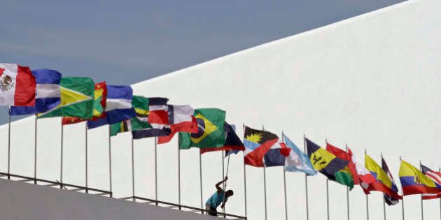 A worker paints a wall below a set up of the flags of the countries that will participate in the upcoming Summit of the Americas outside of the Atlapa Convention Center in Panama City, Monday, April 6, 2015. The venue will host the seventh Summit of the Americas this April 10-11, attended by Western Hemisphere leaders. (AP Photo/Arnulfo Franco)