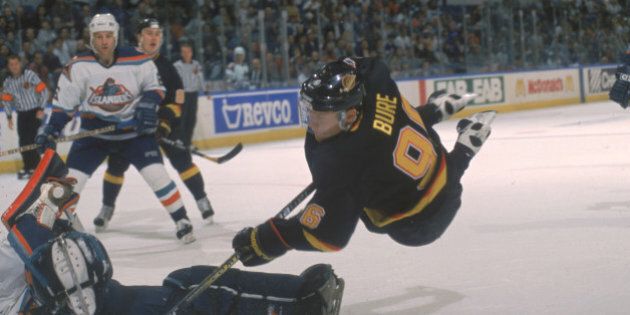Russian hockey player Pavel Bure of the Vancouver Canucks sails through the air as he tries to score on the New York Islanders goalie, Uniondale, New York, 1995-96 season (Photo by Bruce Bennett Studios/Getty Images)
