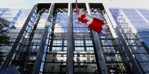 The Canadian flag flies outside the Bank of Canada building in Ottawa, Ontario, Canada, on Wednesday, Oct. 23, 2013. Bank of Canada Governor Stephen Poloz surprised investors by dropping language about the need for future interest rate increases that had been in place for more than a year, citing greater slack in the economy, while keeping his main policy rate unchanged. Photographer: Patrick Doyle/Bloomberg via Getty Images