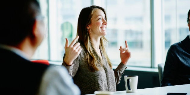 Smiling businesswoman leading project discussion during meeting with coworkers at office conference room table