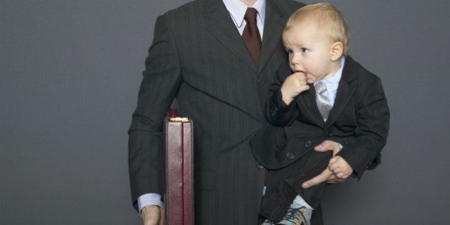 Businessman holding baby son (18-24 months) and briefcase under arm