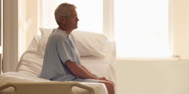 50s man sitting on hospital bed