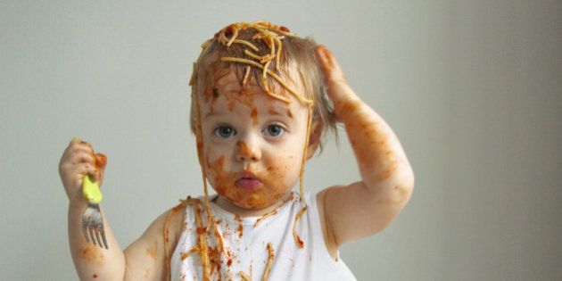 Baby boy getting messy eating spaghetti