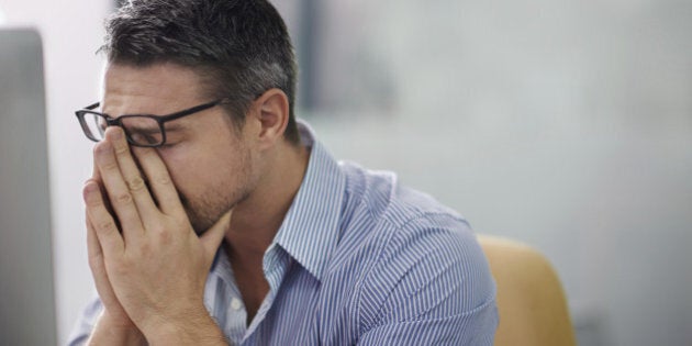 A cropped shot of a stressed businessman sitting at his desk