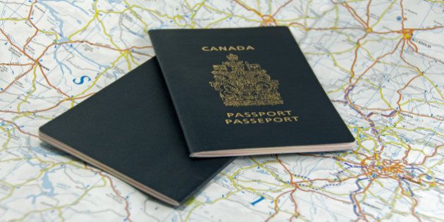 A pair of closed Canadian Passports laid upon a map.