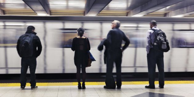 People standing on a platform, waiting for a subway train to arrive. Toronto TTC, Ontario, Canada.